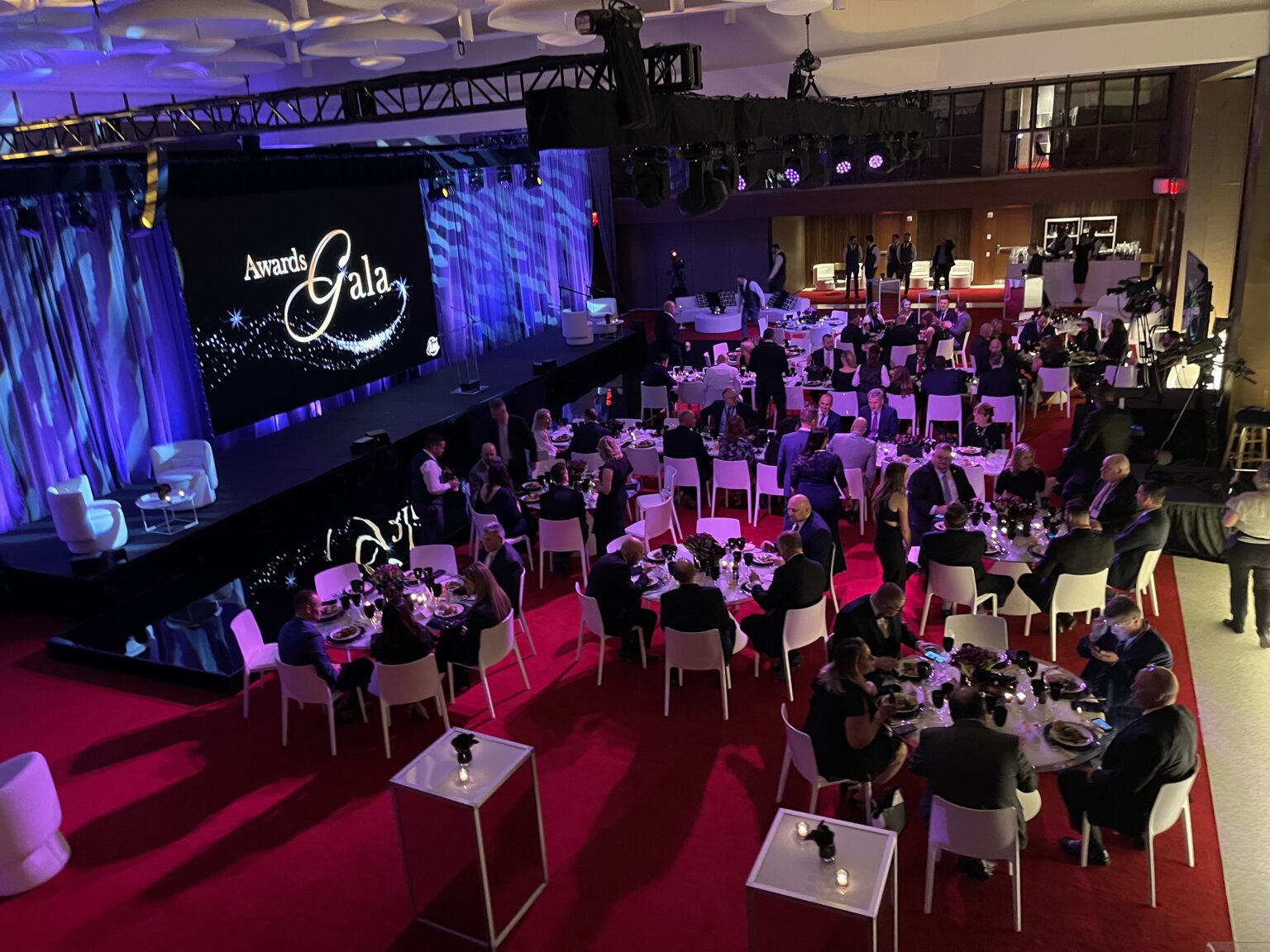 Overhead flown truss, chain motors and lighting rigging for a confidential annual global meeting at the TWA Hotel.